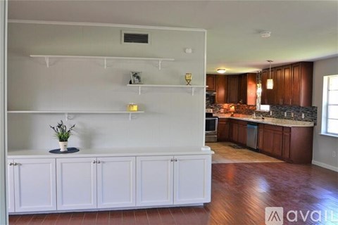 A kitchen with white cabinets and a wooden floor.