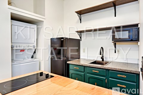 A kitchen with a black fridge and a wooden stove top.