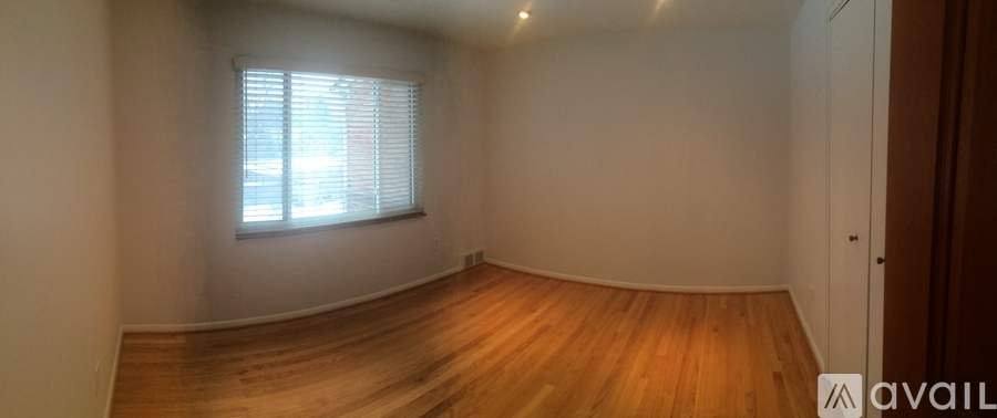 A room with wooden flooring and a window with blinds.