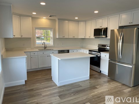 A kitchen with white cabinets and a wooden floor.