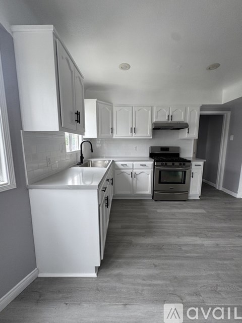 A kitchen with white cabinets and a wooden floor.