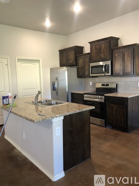A kitchen with dark wood cabinets and a granite countertop.