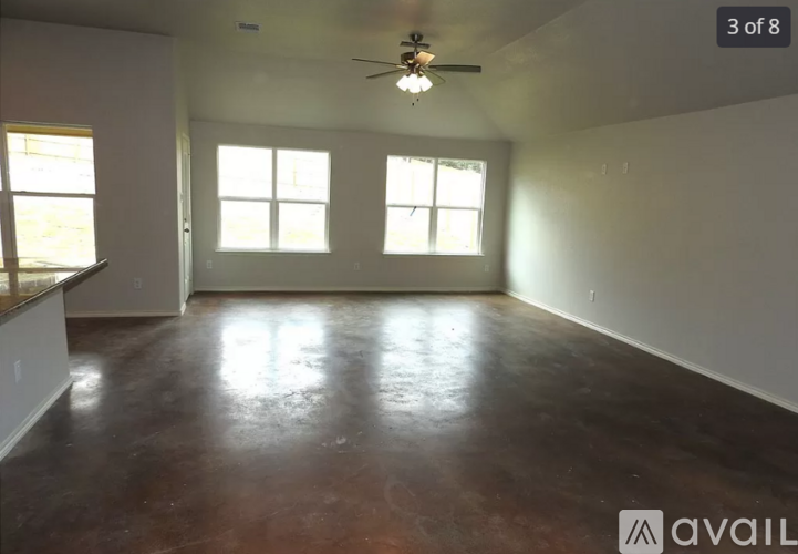 A room with a brown floor and a ceiling fan.