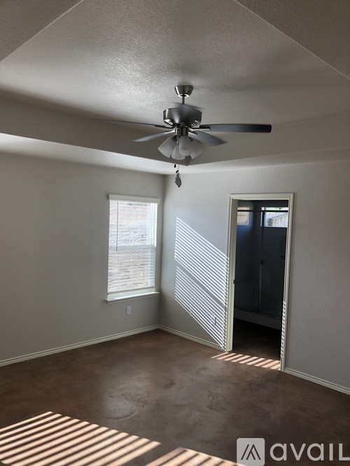 A room with a ceiling fan and a window with blinds.