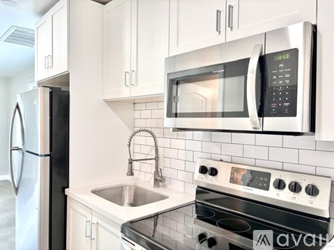 A modern kitchen with a stainless steel refrigerator, a microwave above the stove, and a sink with a faucet.