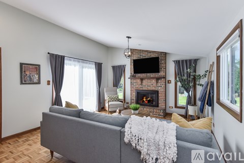 A living room with a grey couch and a fireplace.