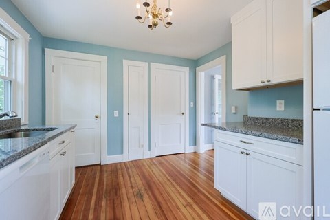 A kitchen with white cabinets and a wooden floor.