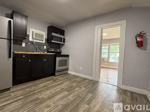 A kitchen with a refrigerator, microwave, oven, and cabinets.