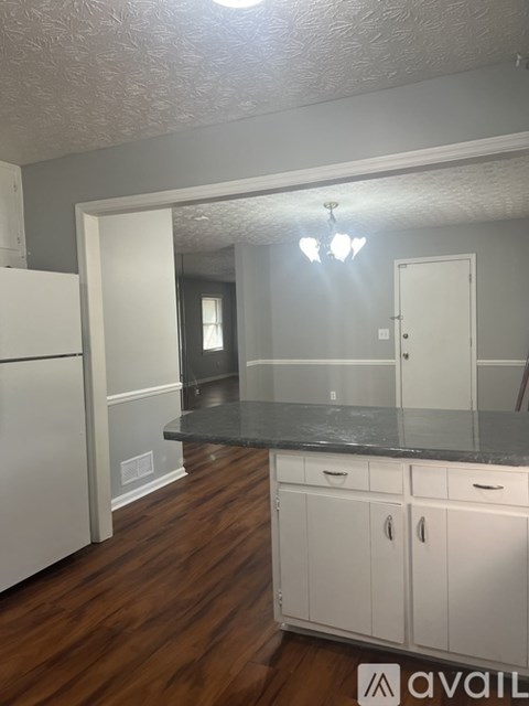 A kitchen with white cabinets and a refrigerator.