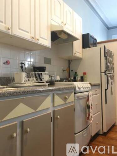 A kitchen with white cabinets and a white fridge.