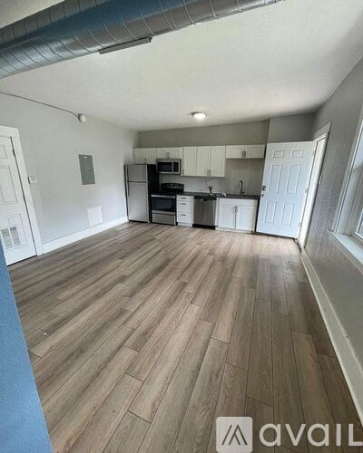 A spacious kitchen with wooden flooring and white cabinetry.