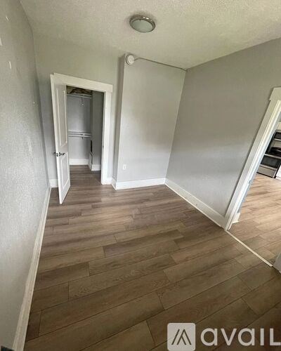 A room with wooden flooring and a doorway leading to another room.