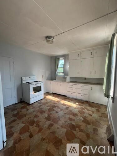A kitchen with a tile floor and white cabinets.