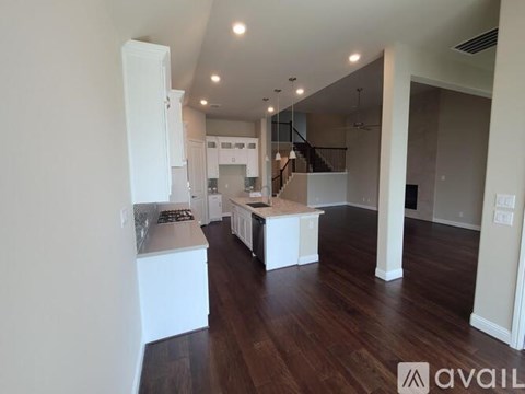 A spacious kitchen with white cabinets and a wooden floor.