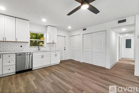A kitchen with white cabinets and a wooden floor.