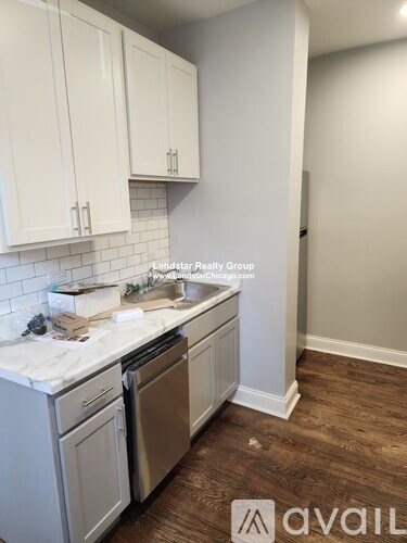 A kitchen with white cabinets and a wooden floor.