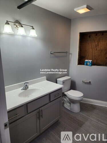 A bathroom with a toilet, sink, and a light on the wall.