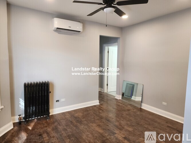 A room with a fan, air conditioner, and wood flooring.