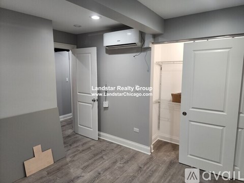 A room with a grey wall and a white door is shown.