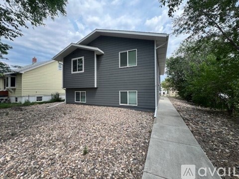 A house with a grey siding and a tree in front of it.