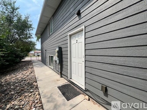 A grey building with a white door and a mailbox on the left.