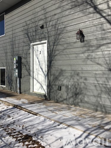 A grey building with a white door and a mailbox on the left.