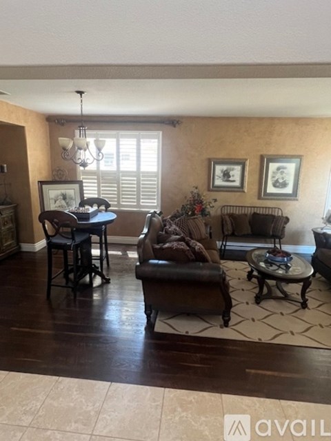 A living room with a brown couch, a coffee table, and a dining table with chairs.