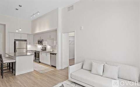 A modern kitchen with a white couch in the living room.