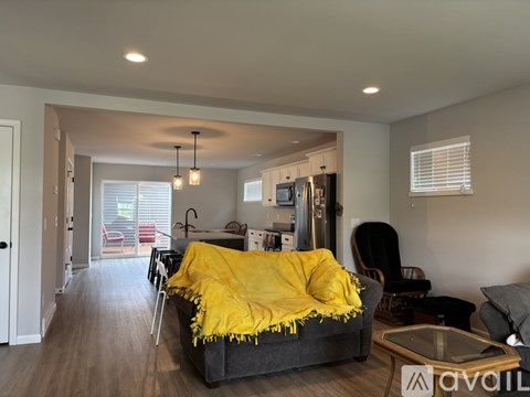 A living room with a grey couch and a yellow throw blanket.