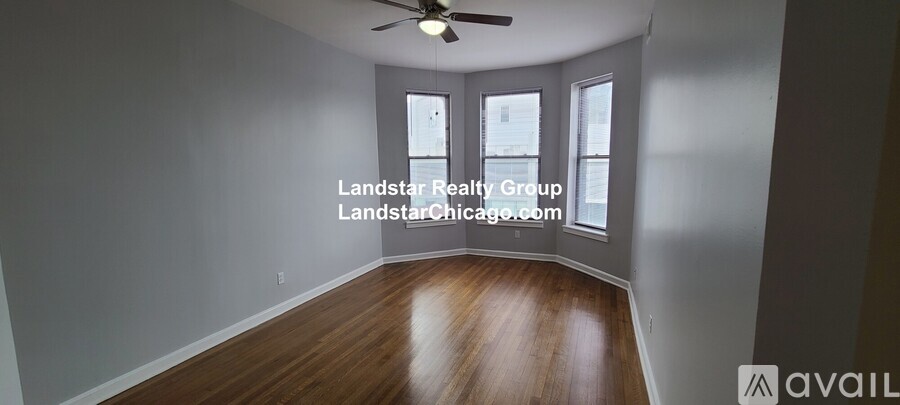 A spacious room with wooden floors and a ceiling fan.