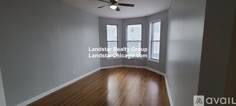 A spacious room with wooden floors and a ceiling fan.