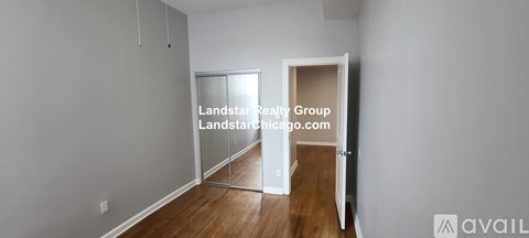 A room with a wooden floor and white walls, with a doorway leading to another room.