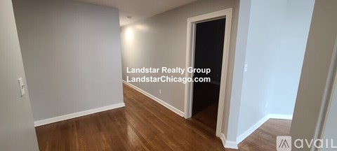 A room with a wooden floor and a doorway leading to another room.