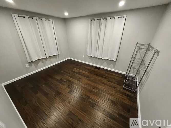 A room with wooden flooring and white curtains.