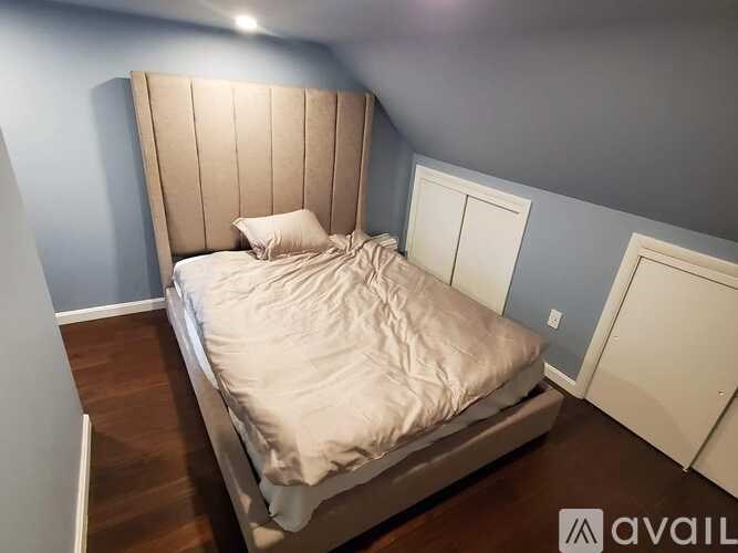 A bed with a wooden headboard and white pillow is in a room with blue walls.