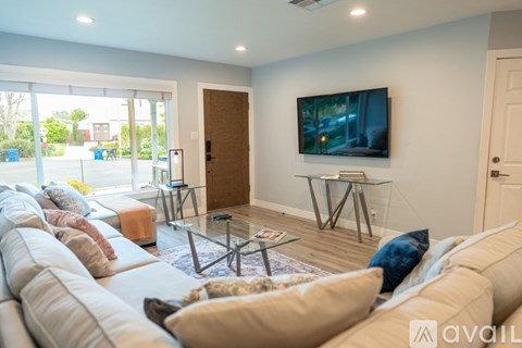 A living room with a large couch and a flat screen TV mounted on the wall.