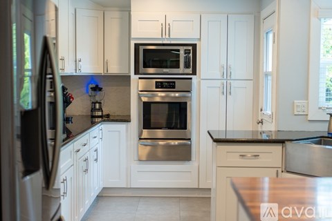 A kitchen with white cabinets and a black countertop.