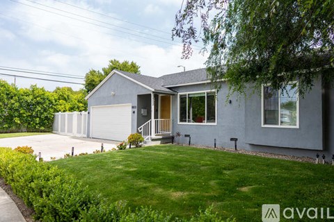 A house with a grey exterior and a white garage door is for sale.