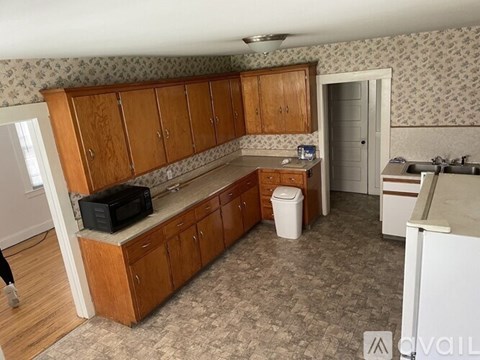 A kitchen with wooden cabinets and a black microwave on the counter.