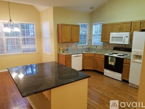 A kitchen with wooden cabinets and black countertops.