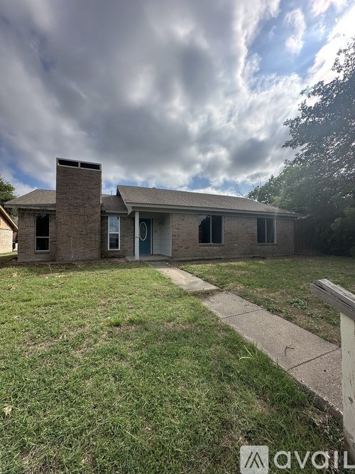 A house with a green lawn and a cloudy sky in the background.