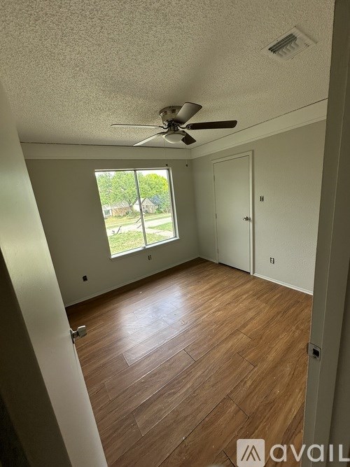 A room with a ceiling fan and wooden flooring.