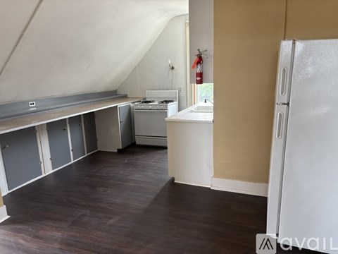 A kitchen area with a refrigerator, sink, and cabinets.