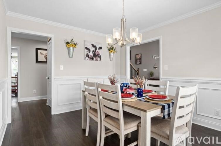A dining room with a table set for two and a chandelier hanging from the ceiling.