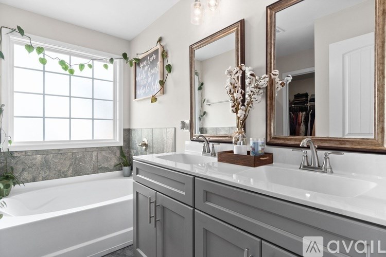 A bathroom with a tub, sink, and mirror.