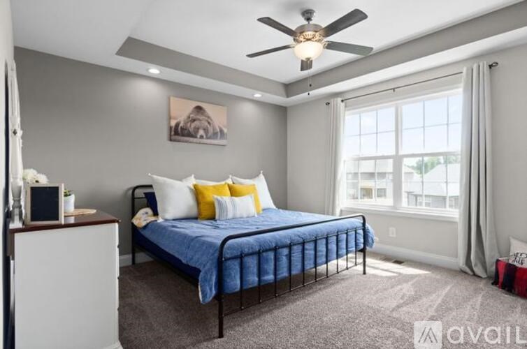 A bedroom with a blue bedspread and a ceiling fan.