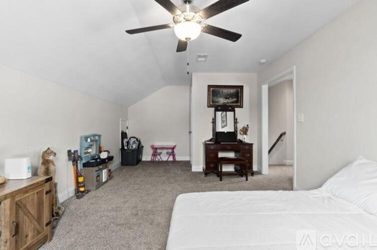 A bedroom with a bed, dresser, and a ceiling fan.