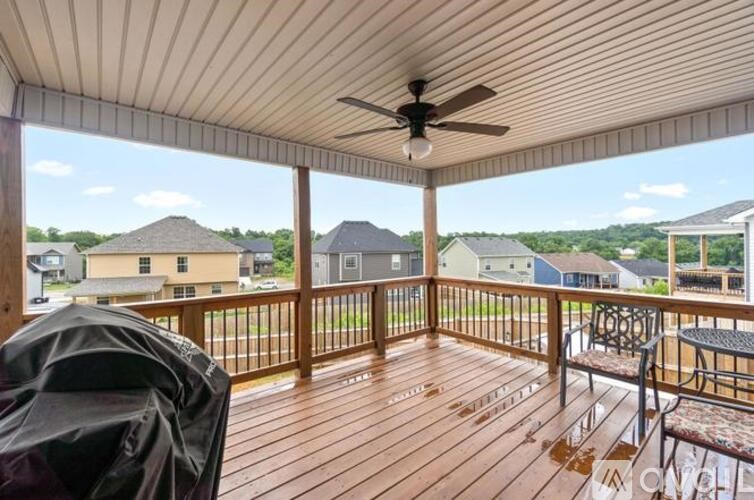 A covered deck with a ceiling fan and a table and chairs.