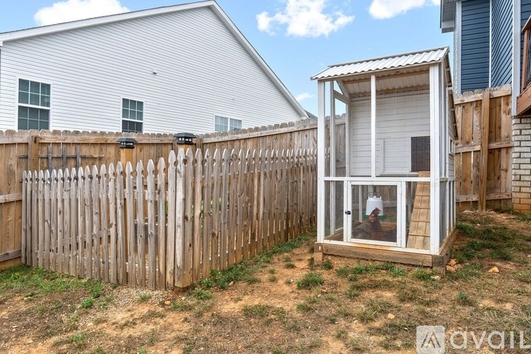 A wooden fence surrounds a small white building with a glass door.