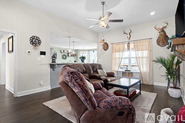 A living room with a brown couch and a ceiling fan.